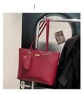 Close-up of red pebbled leather tote set with gold metal plaque and matching pouch