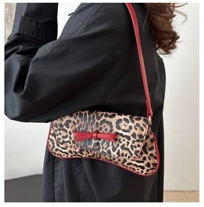 Close-up of leopard print baguette bag featuring red bow detail and slim shoulder strap