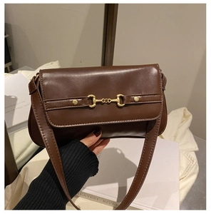 Close-up of a dark brown leather shoulder bag featuring a gold horsebit hardware buckle