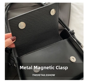 Dettaglio delle fibbie magnetiche in metallo argentato sulla borsa a spalla nera