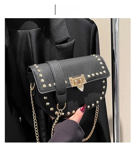 Détail du sac bandoulière noir avec rivets dorés et élégante bandoulière en chaîne