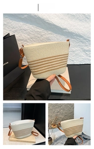 Detailed macro view of beige straw woven bucket bag with brown stripes and leather strap
