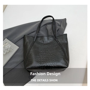Detailed close-up of black crocodile pattern leather tote bag on wool coat texture