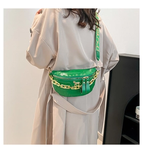 Detail der grünen Gürteltasche mit Kroko-Prägung, Goldkette und gemustertem Gurt
