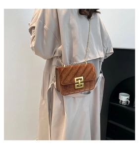 Gros plan du sac bandoulière en velours marron avec texture matelassée et chaîne