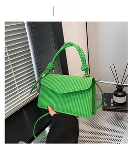 Detail of green woven crossbody bag with thick knot handle and textured envelope flap