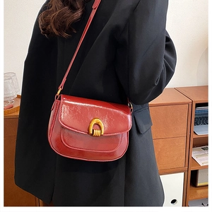 Close-up of wine red saddle bag featuring a textured leather finish and golden buckle