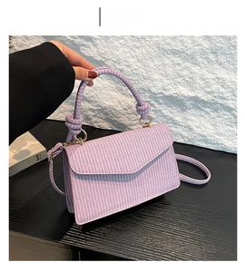 Detail shot of purple woven handbag featuring texture craftsmanship and metal ring handle