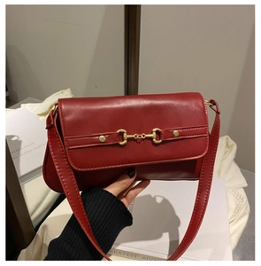 Detail of red glossy leather shoulder bag featuring golden horsebit hardware buckle