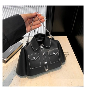 Close-up of jacket-shaped black leather bag with white stitching and silver chain