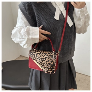 Fashionable leopard print and red leather shoulder bag shown on model for crossbody use