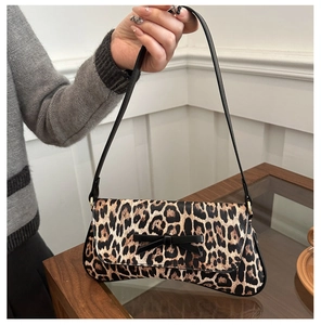 Detail of leopard print underarm bag featuring a black bow and golden metal hardware