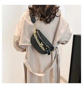 Detail der schwarzen Brusttasche mit Krokoprägung, Goldkette und bedrucktem Gurt am Model