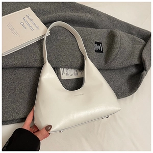 Detail showing metal protective feet and brand logo on white crescent hobo bag