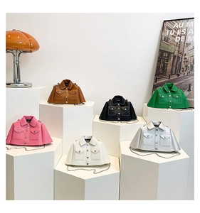 Close-up of jacket-shaped leather crossbody bags with contrast stitching and metal chains