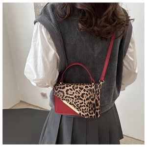 Detail of a chic leopard print shoulder bag with red leather trim and gold metal accent