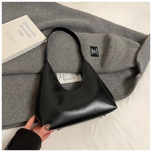 Macro shot of glossy black leather hobo bag with zipper and branded logo detail
