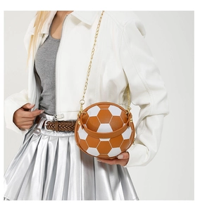 Detail of soccer ball shaped crossbody bag with brown leather handle and gold chain strap