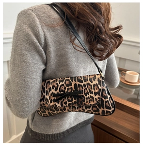 Close-up of stylish leopard print baguette bag with a black bow and sleek shoulder strap