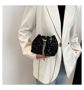 Close-up of black sequined bucket bag with silver chain strap and pearl drawstring detail
