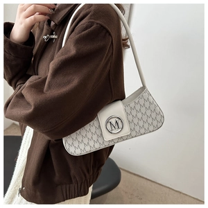 Detail of white leather underarm bag with M monogram print and silver metal logo buckle