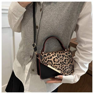 Close-up of leopard print patchwork handbag with gold metal bar and red edge paint detail