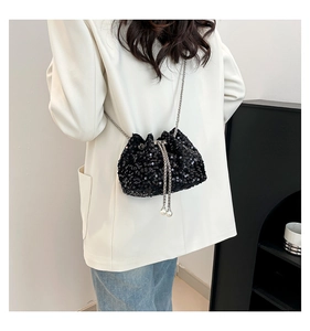 Detail of black sequin bucket bag with silver chain and pearl drawstring on a model
