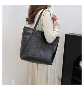 Detail of black crocodile pattern tote bag shown in a minimalist lifestyle setting