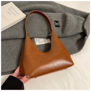 Close-up of brown textured leather crescent bag with brand logo and metal base studs