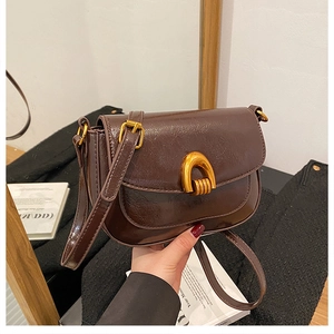 Detailed macro view of dark brown oil leather saddle bag with vintage gold metal buckle
