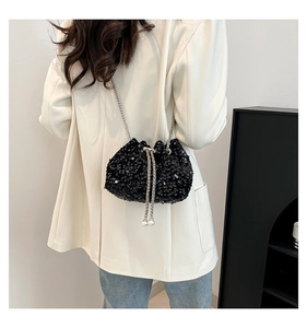 Detail of black sequined bucket bag with elegant pearl drawstring on a crossbody chain