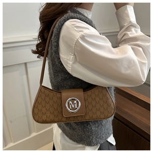 Detail of a brown retro underarm bag with M-letter monogram and silver magnetic clasp