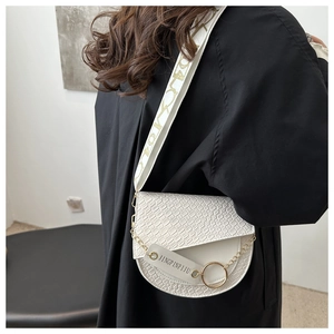 Détail du sac selle blanc avec texture croco, chaîne dorée et large bandoulière