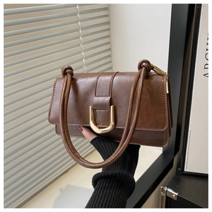 Dettaglio borsa baguette vintage marrone con fibbia a ferro di cavallo oro e tracolla annodata
