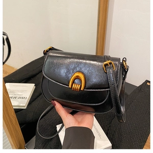 Close-up of black oil-wax leather saddle bag with golden horseshoe metal buckle
