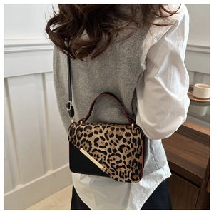 Detail of leopard print crossbody bag with gold metal trim and red painted edge finish