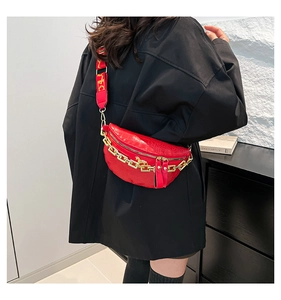 Détail du sac ceinture rouge à motif crocodile avec chaîne dorée et large sangle