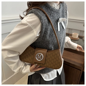 Close-up of brown monogram underarm bag with vintage M-pattern and silver metal buckle