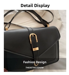 Close-up of black leather crossbody bag featuring a golden horseshoe buckle and fine stitching