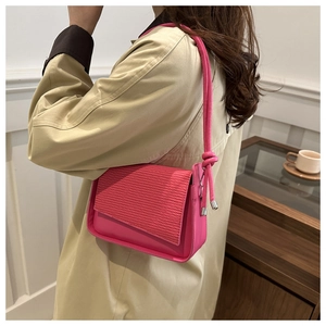 Dettaglio borsa rosa con patta strutturata a onde e tracolla con nodi decorativi