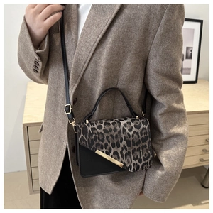Detail of leopard print crossbody bag with gold metal bar on a brown vintage blazer