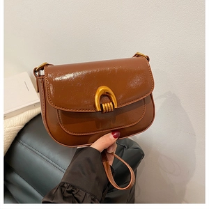 Detail of a brown vintage saddle bag featuring glossy oil wax leather and a gold U-buckle
