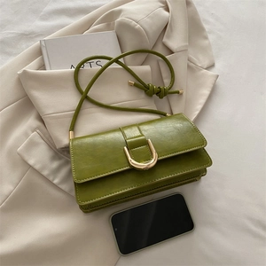 Borsa baguette retrò verde erba con fibbia dorata su elegante sfondo blazer