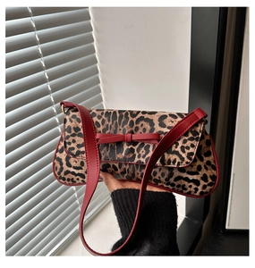 Close-up of leopard print baguette bag with red leather bow and contrast shoulder strap