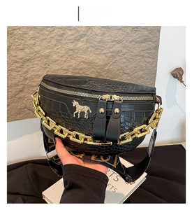 Makrodetail der schwarzen Krokodillederstruktur und des goldenen Pferdemotivs am Satteltasche