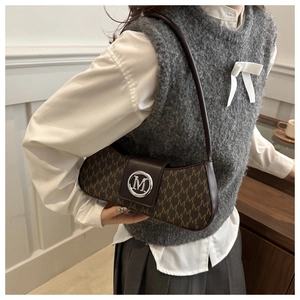 Detail of vintage brown underarm bag with M-letter monogram and silver buckle close-up