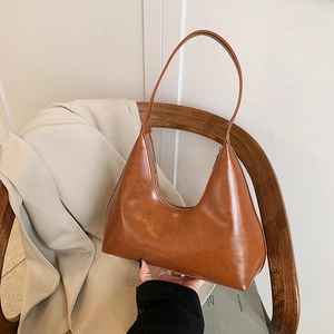 Retro caramel brown crescent hobo bag in glossy leather on a stylish wooden chair