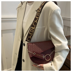 Détail du sac selle rouge vin avec texture crocodile et bandoulière en jacquard