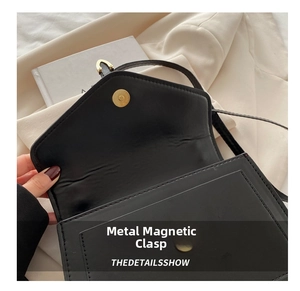 Detail of the golden magnetic snap button on a black leather crossbody square bag
