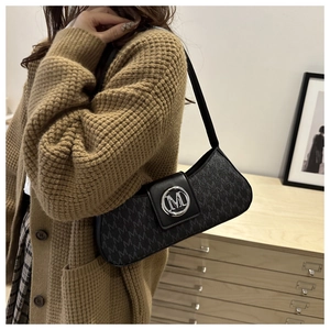 Close-up of black baguette bag featuring monogram M texture and silver metal logo